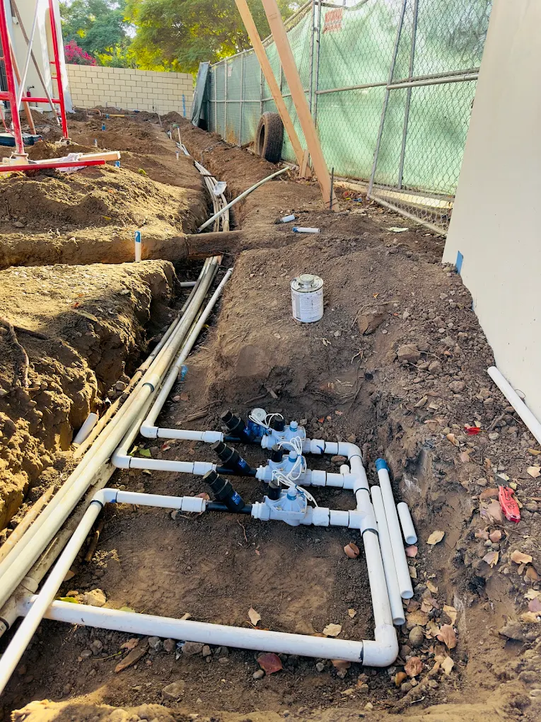 A trench with drainage lines running along the side of a house